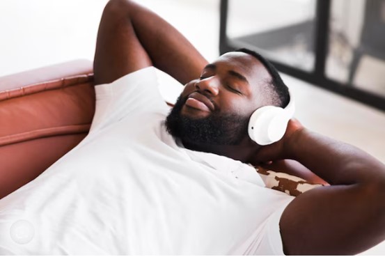 A black man listening to music while relaxing on a couch. 